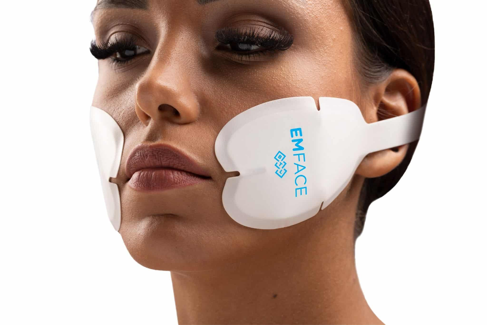 Close-up of EMFACE applicators placed on the cheeks during a needle-free facial treatment.