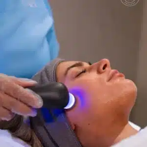 Woman receiving a Dermoregen facial treatment with a skincare device