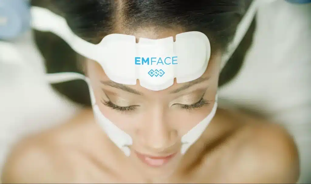 EMFACE applicator pads placed on the forehead and cheeks during a non-surgical facial lifting treatment